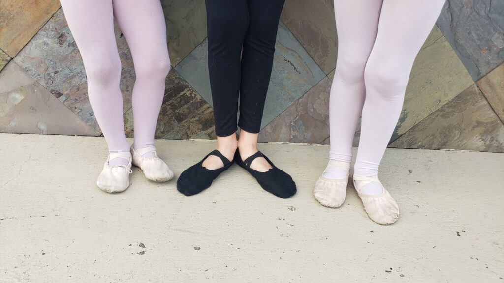 two girls in pink shoes; boy in black ballet shoes