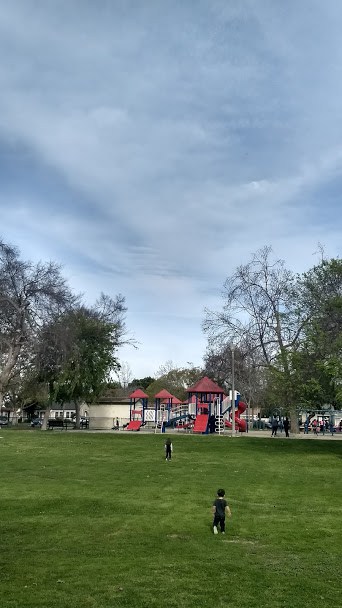 Two children running towards a play area in a park