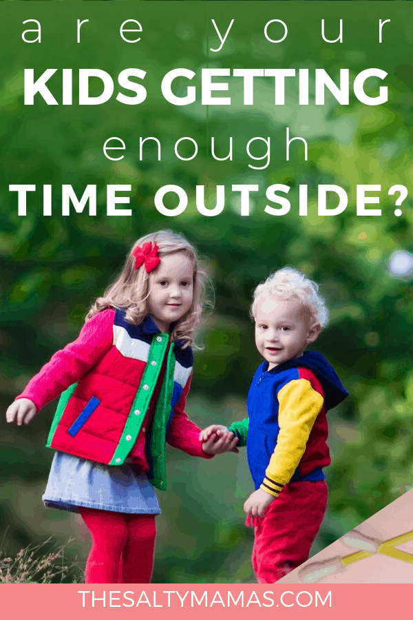 Two children holding hands facing towards the camera by trees. Text overlay: Are your kids getting enough time outside?