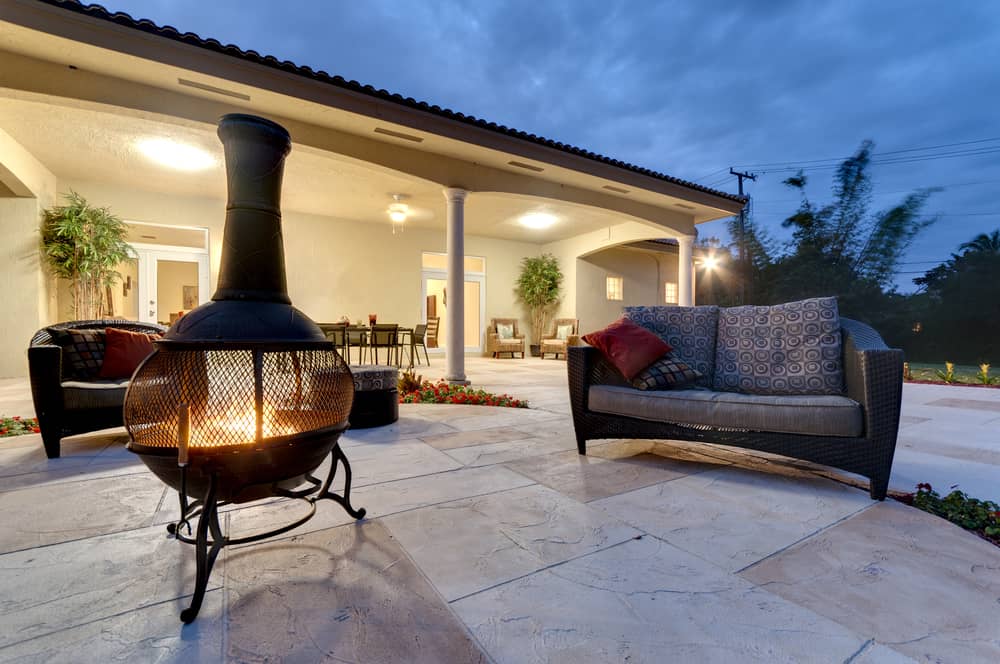 A fire pit lit in a backyard near a couch.