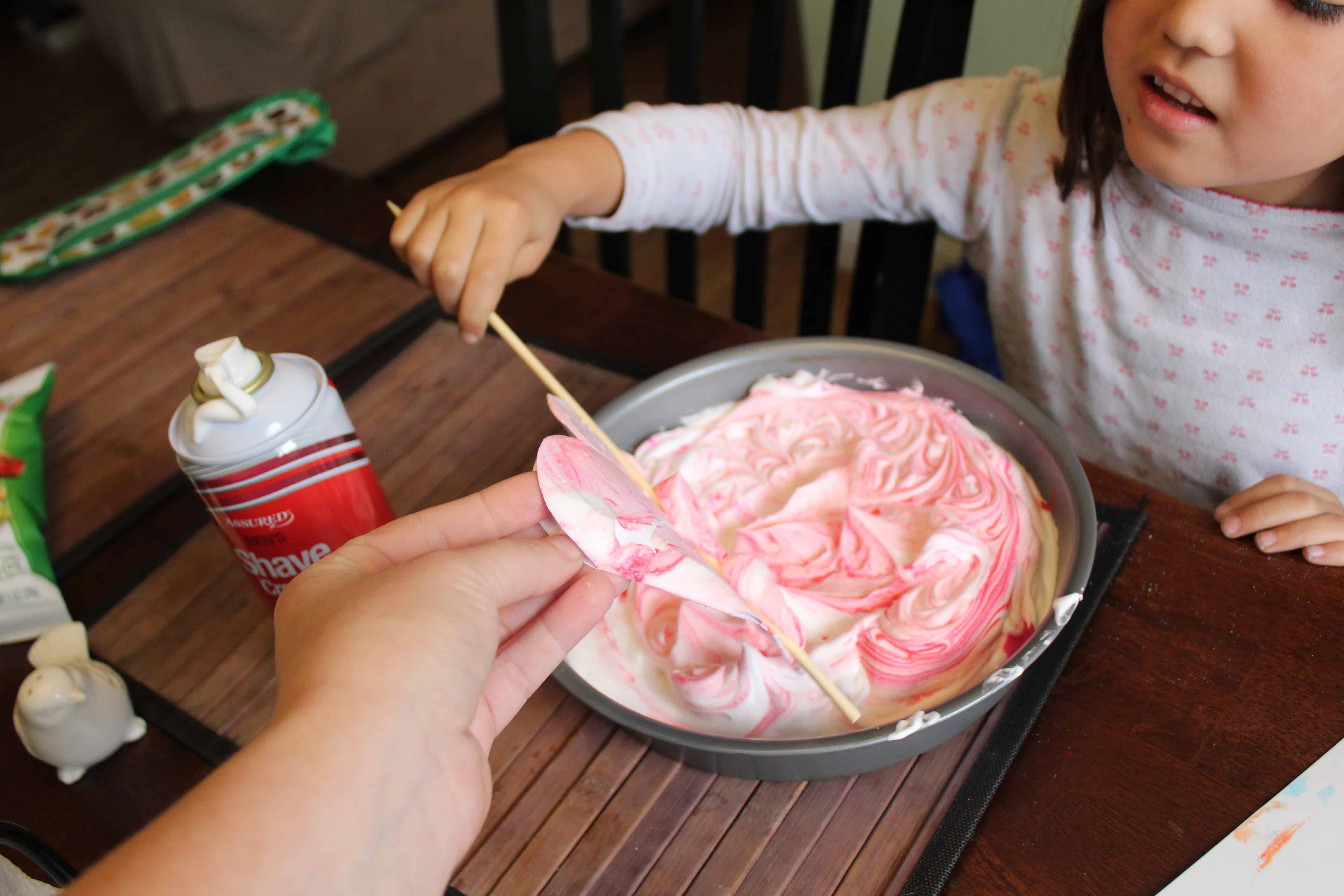 toddler with pie tin full of shaving cream paint