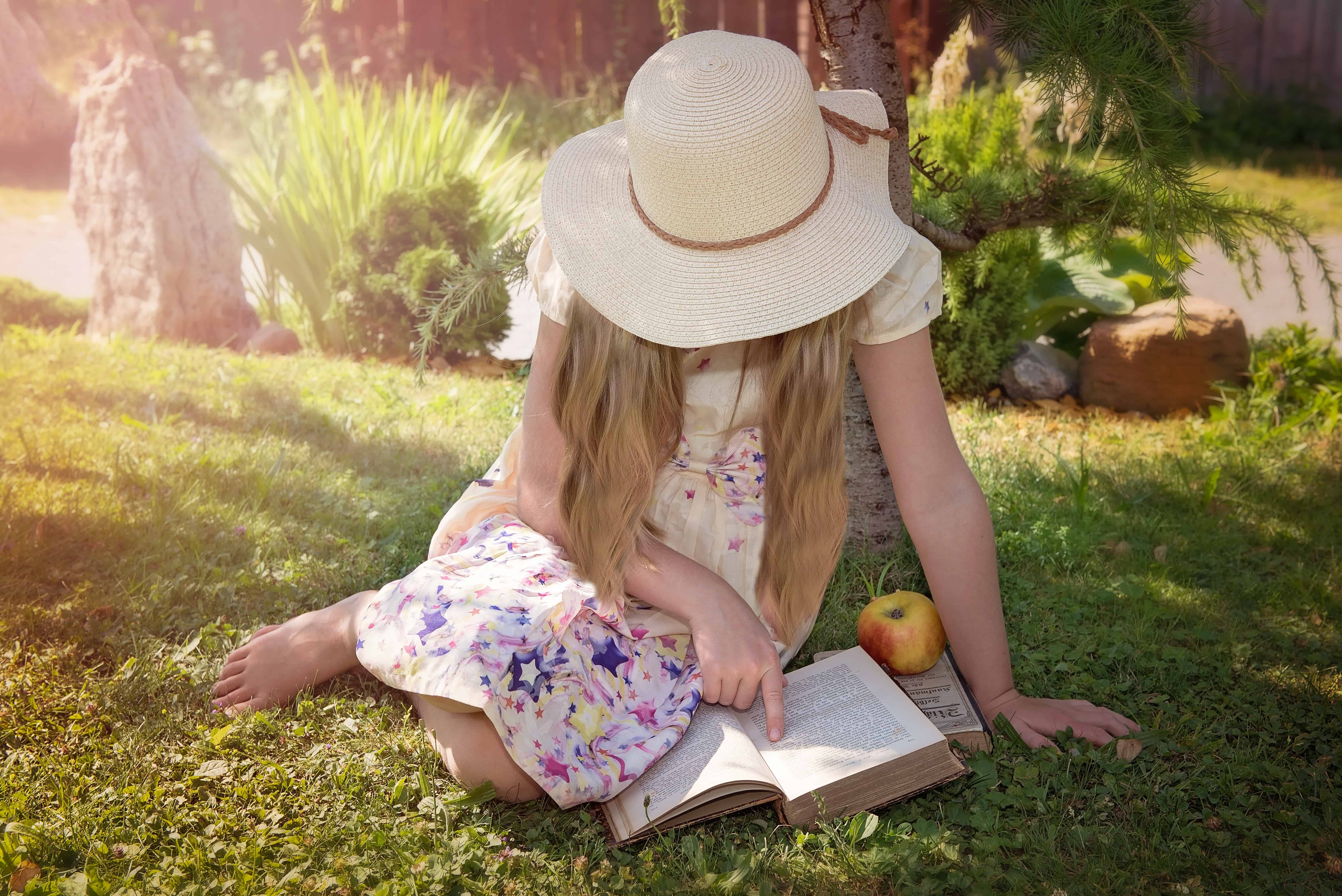 Child sitting in the sun reading a book