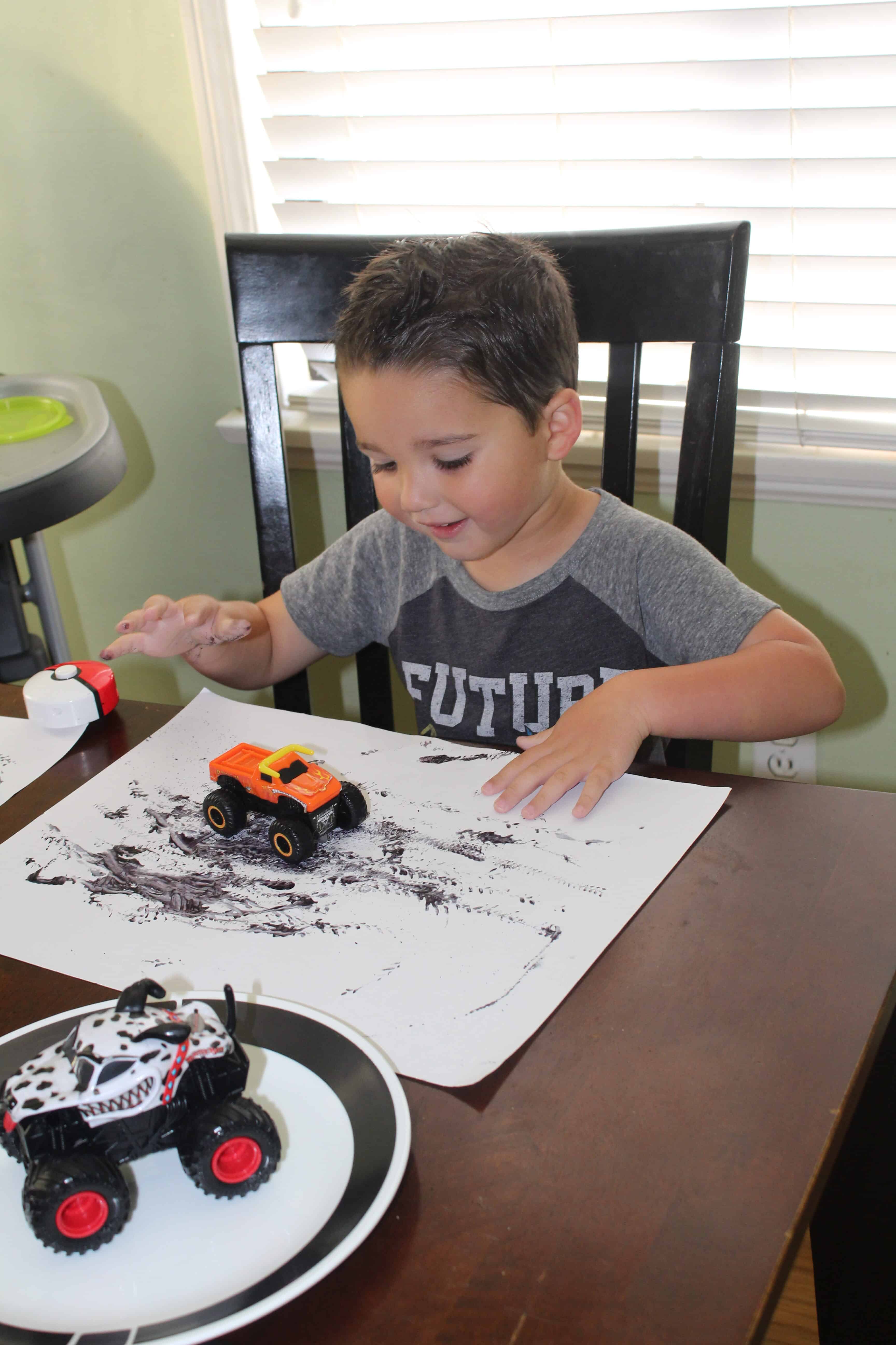 A toddler using a toy car with various patterns on the activity mat