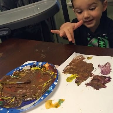 Toddler with a paper plate full of "mud paint"