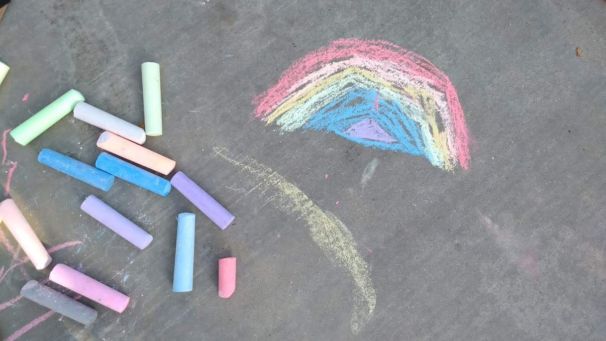 Colored chalk on sidewalk next to a chalk drawn rainbow.