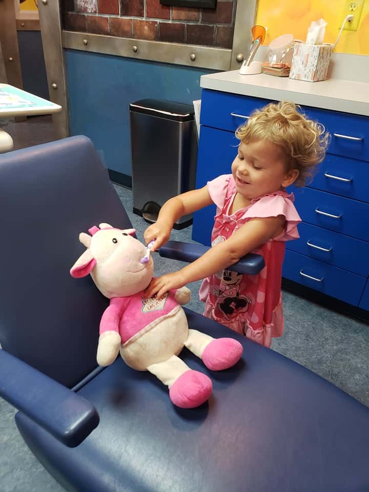 toddler brushing stuffed animal's teeth