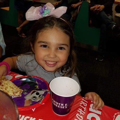 Smiling toddler with Chuck E cheese cup.