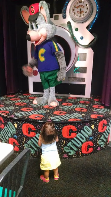 Toddler standing in front Chuck E. Cheese animatronic.