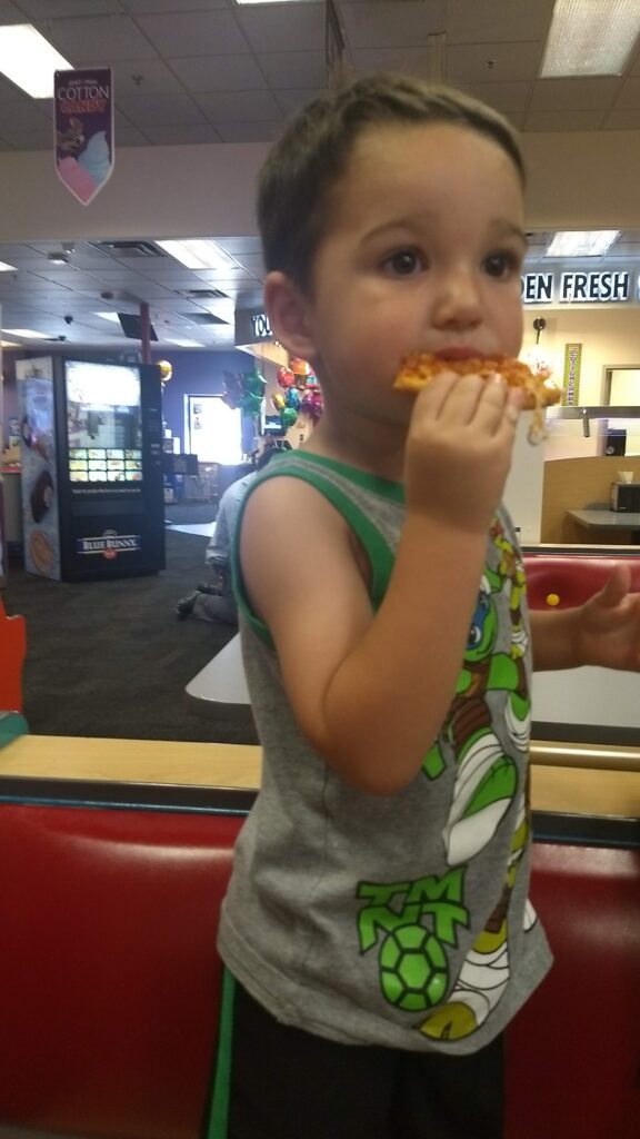 toddler eating pizza at chuck e cheese