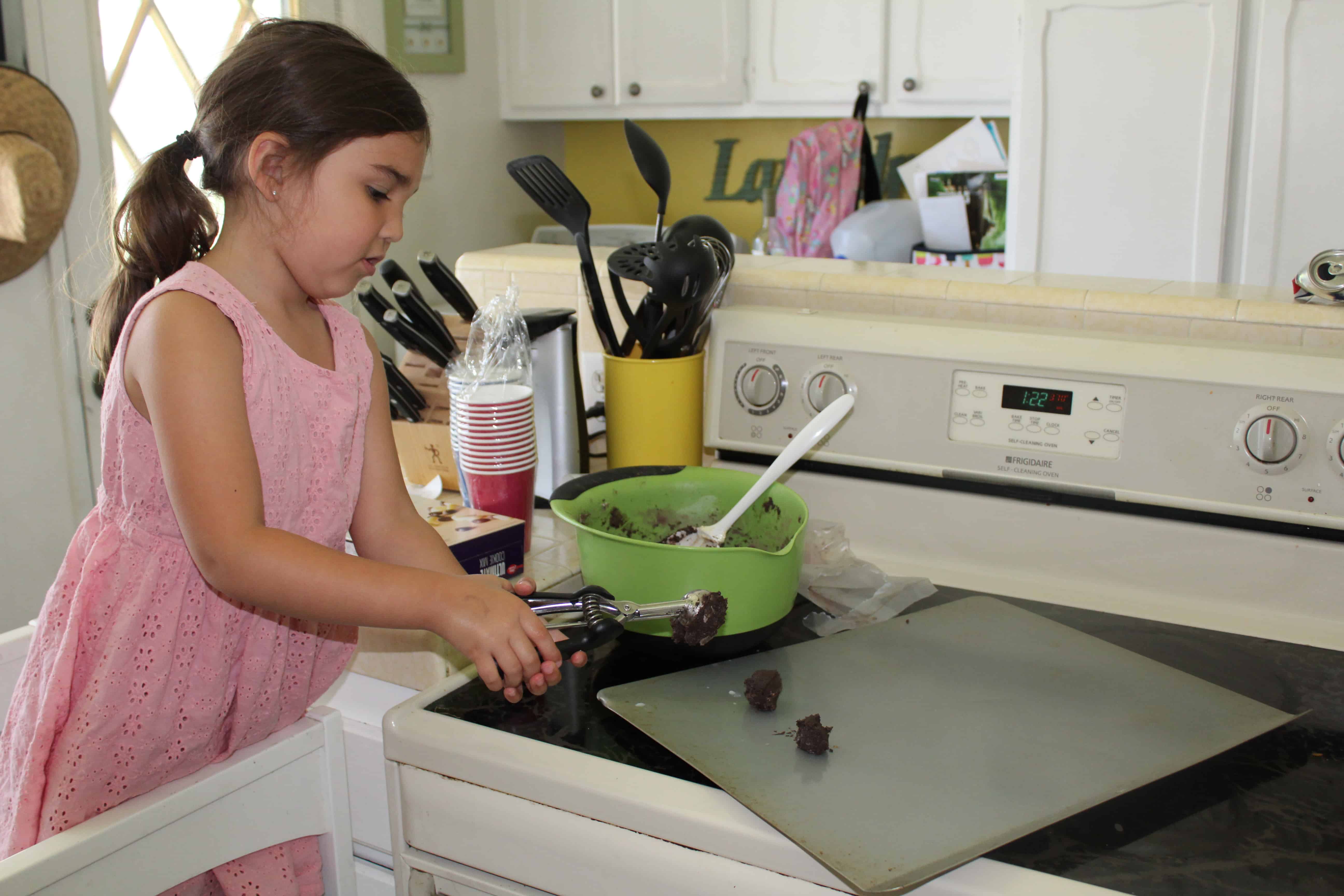 Toddler scooping batter onto a cookie sheet