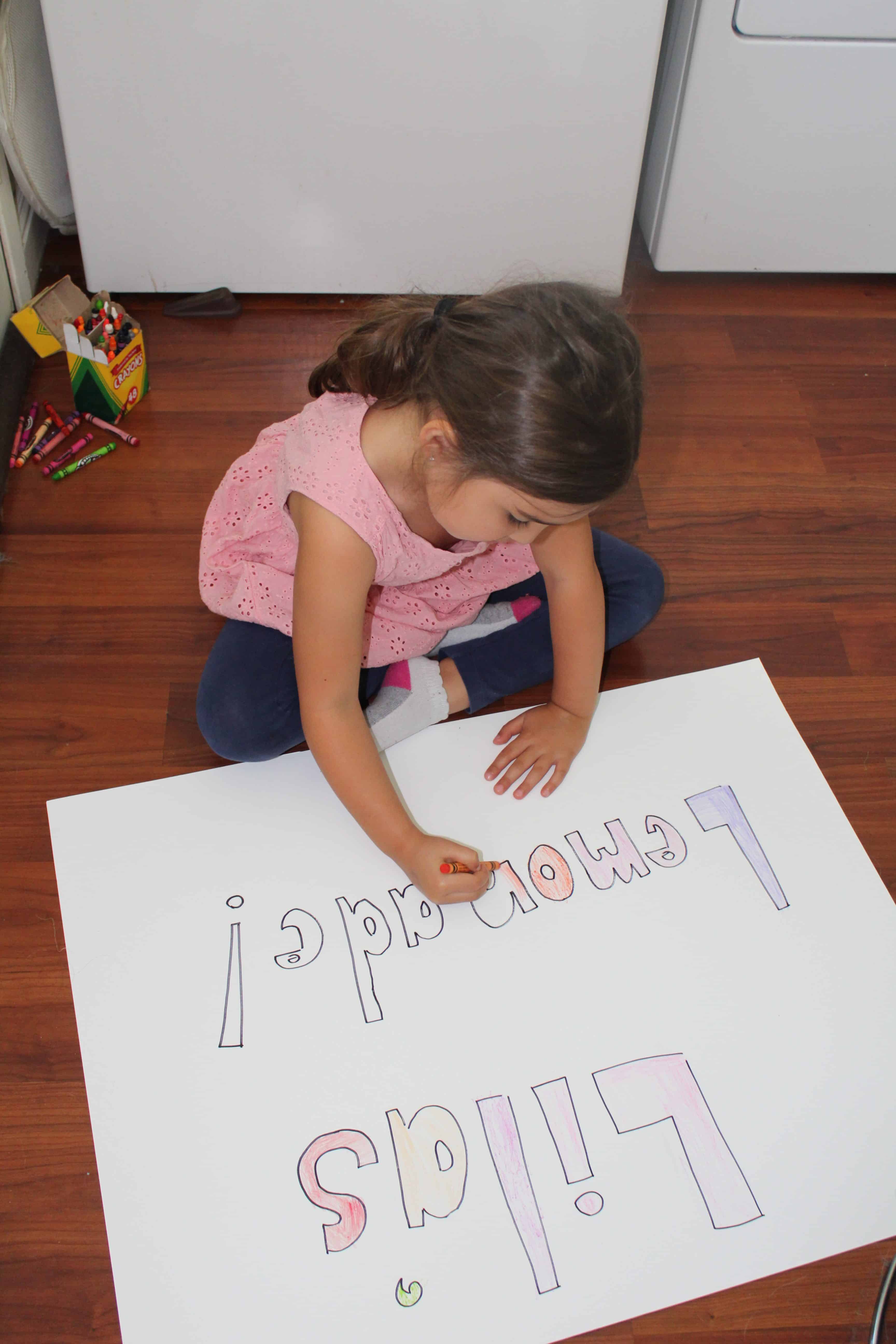 Child coloring lemonade stand sign to advertise