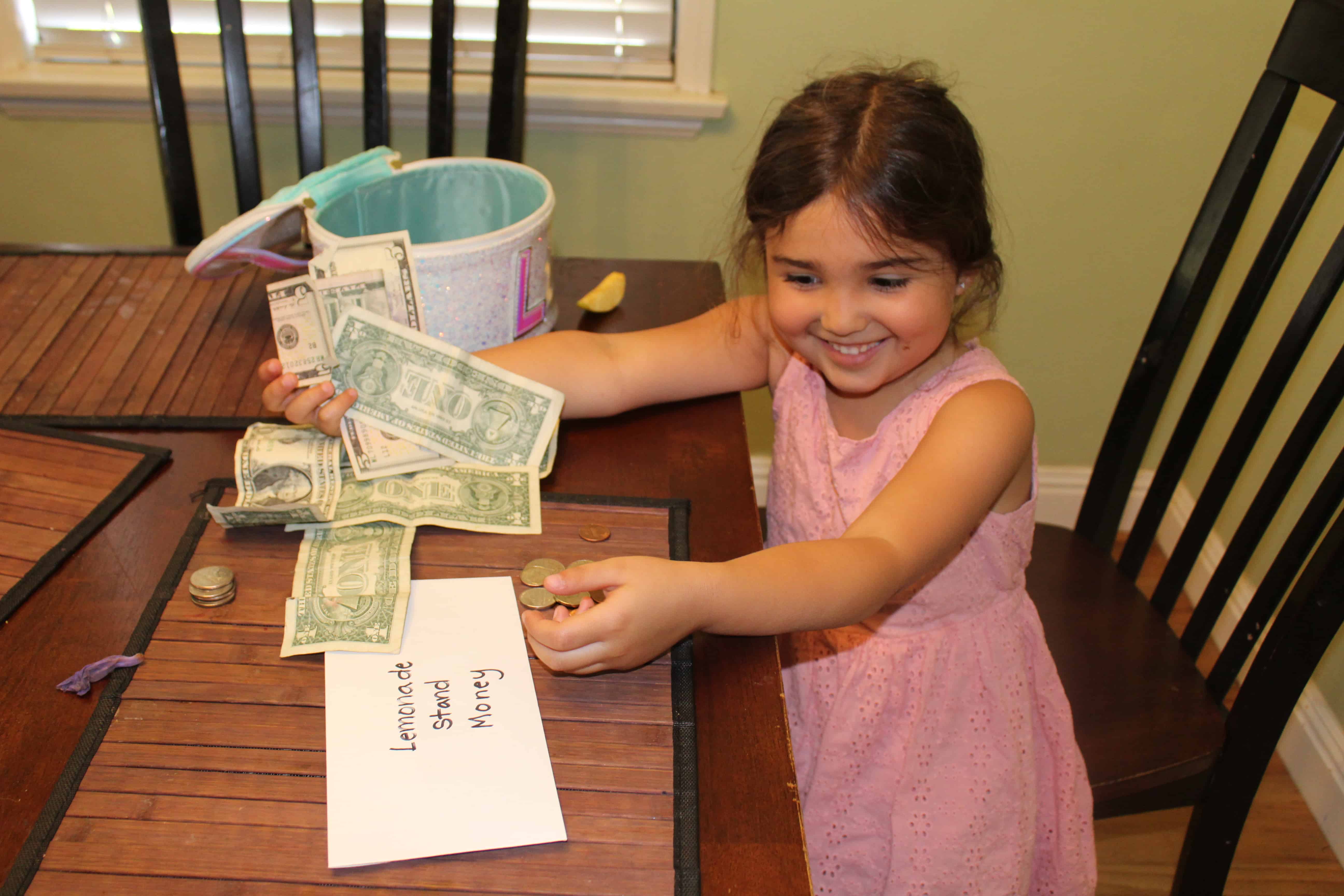 child counting money from her lemonade stand