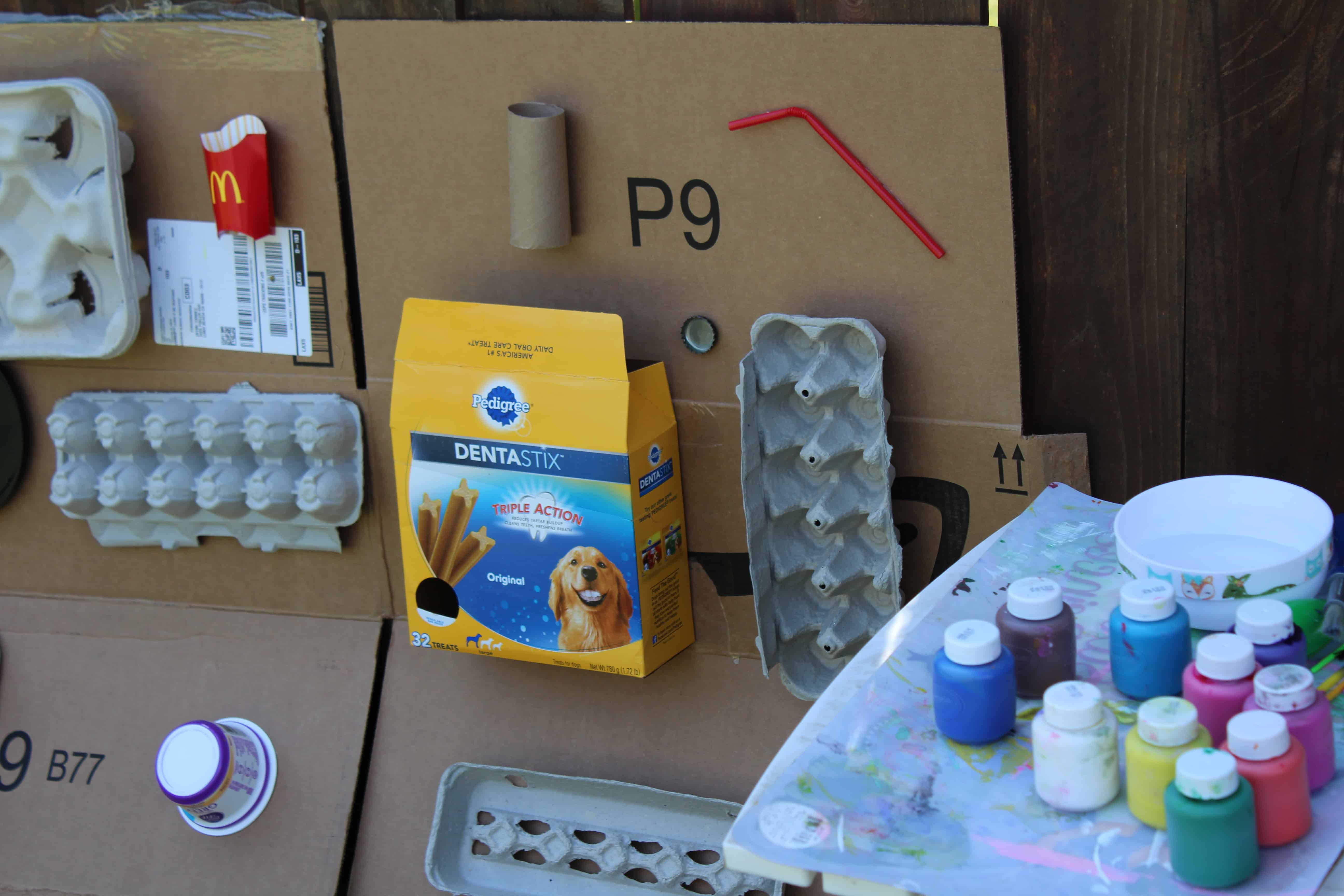 Recycled art materials attached to a flat carboard box. A table of paints for the activities.