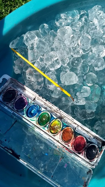 Water table filled with ice with an open case of watercolors on top