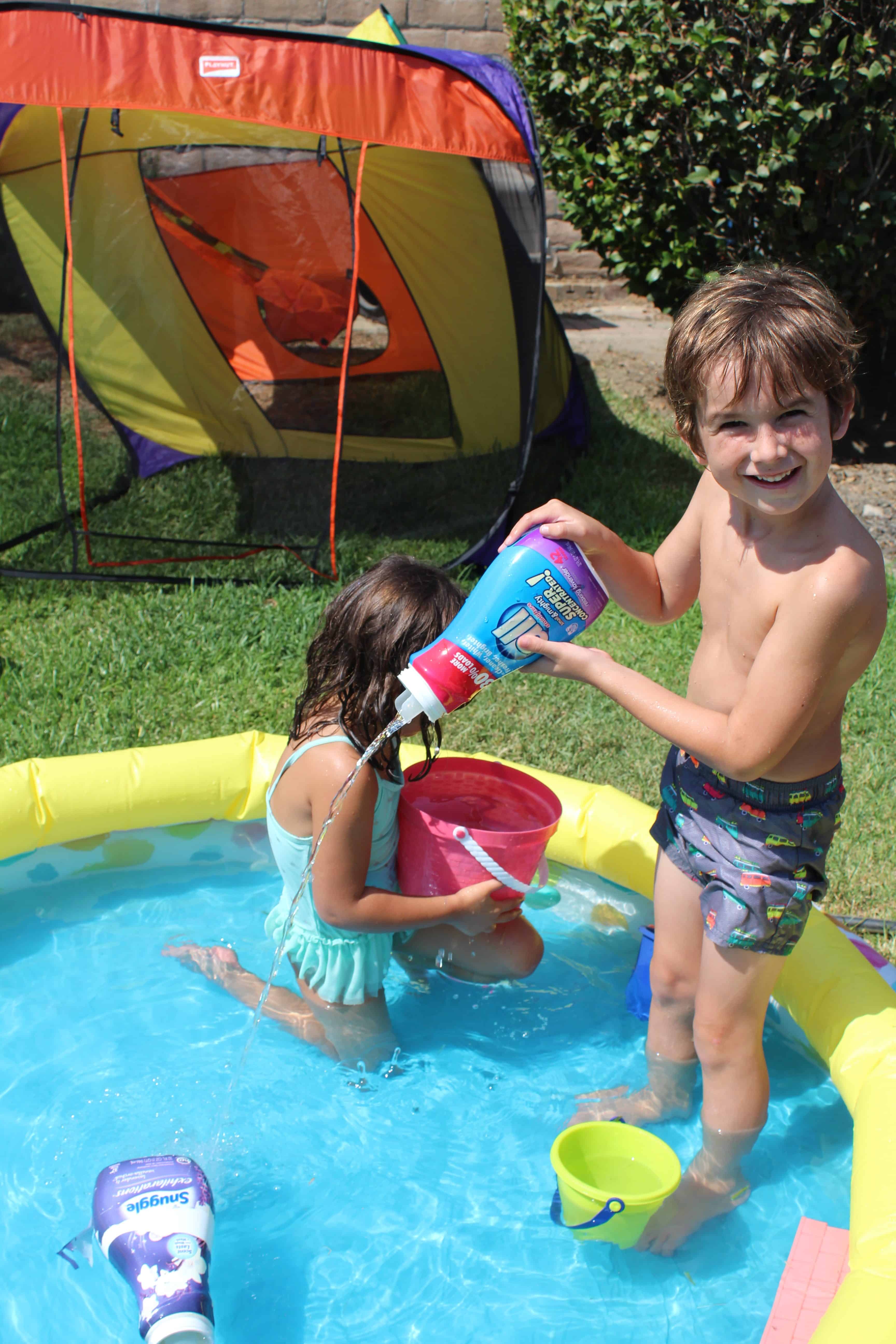 Children playing with recycled materials in a kiddy pool. Using and old softener to pour water into the kiddy pool. 