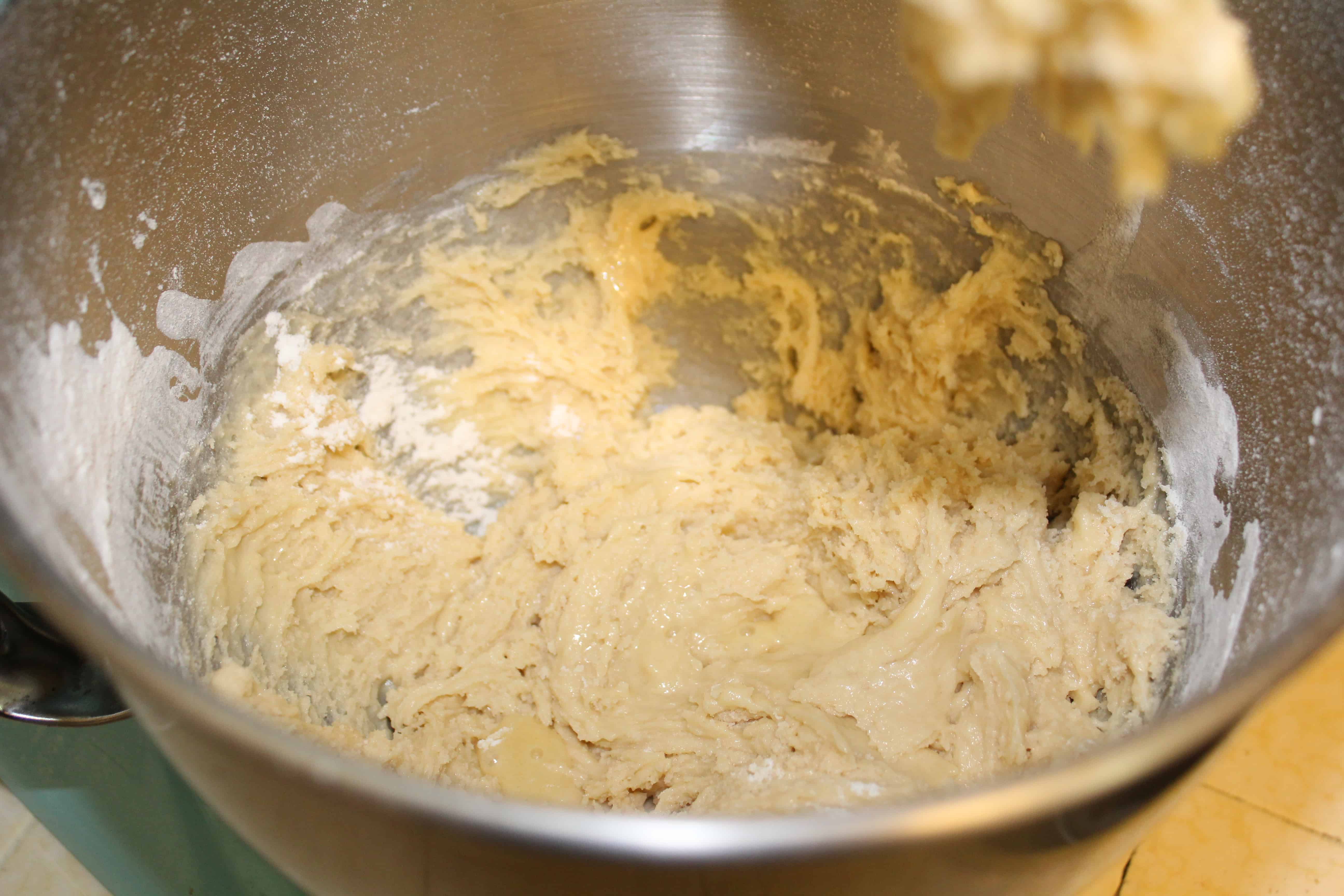 All the ingredients coming together in a mixing bowl making a shaggy dough on the bottom. 