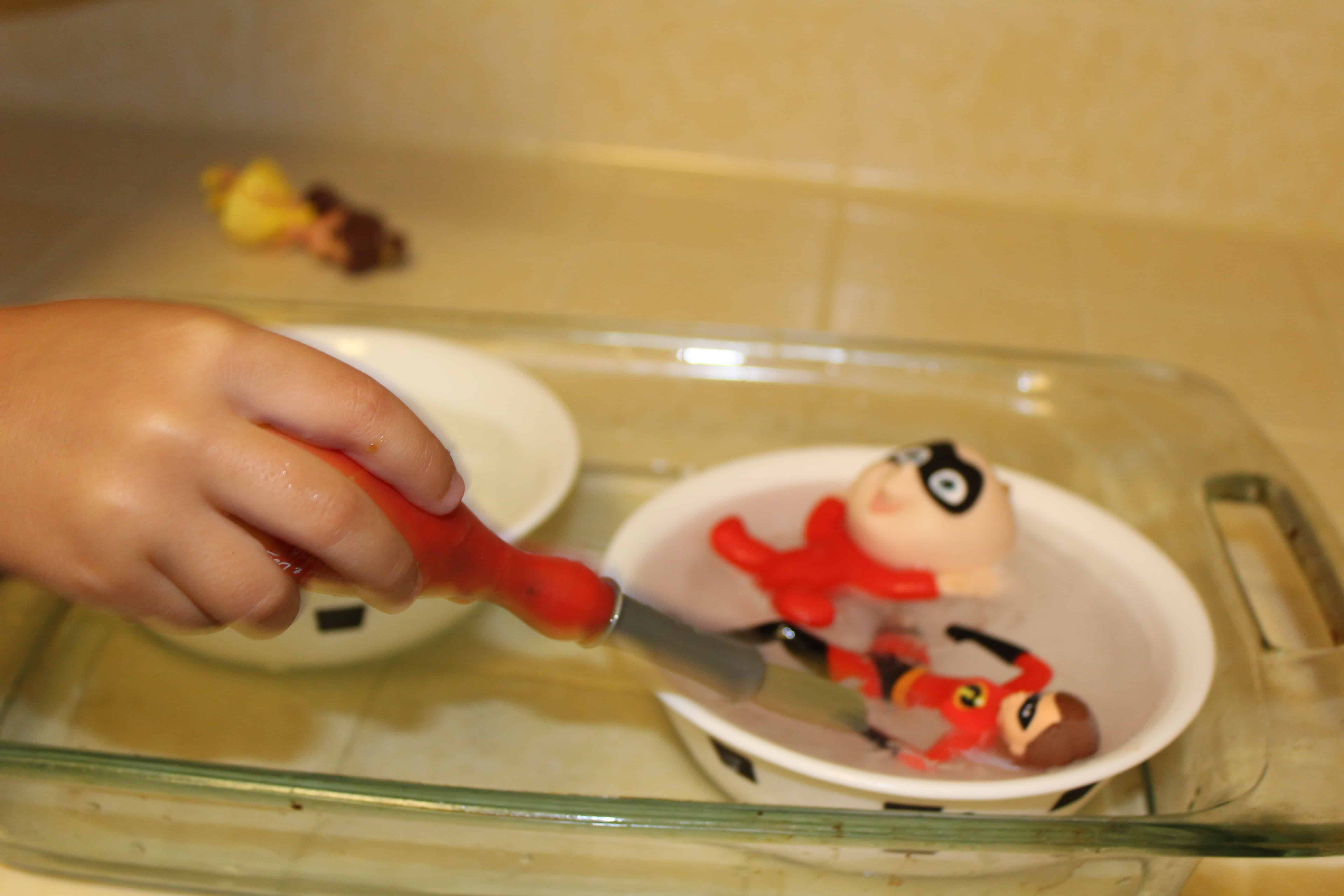 Child using paint brush to spread warm water on ice. 