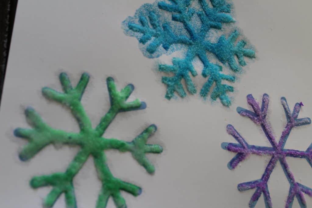 Create snowflakes with this winter process art project featuring Raised Salt Painting. With simple materials and great results, this snowflake art project will be one kids want to repeat again and again. Get the instructions at TheSaltyMamas.com. #snowflake #snowflakeart #winter #wintercrafts #winterart #snowtheme #preschoolsnowtheme #preschoolwintertheme #processart #processartforkids #kidsart