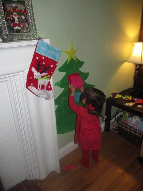 Little girl decorating a small wall decor of a felt Christmas tree.
