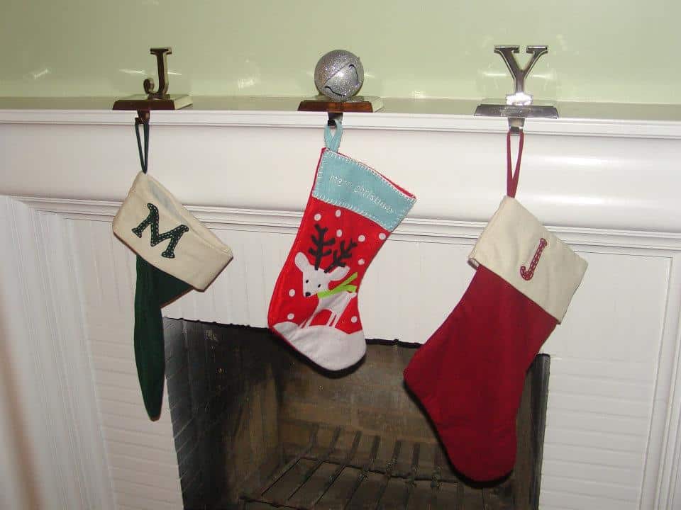 Three stockings hanging in front of the fire play with hangers spelling out JOY