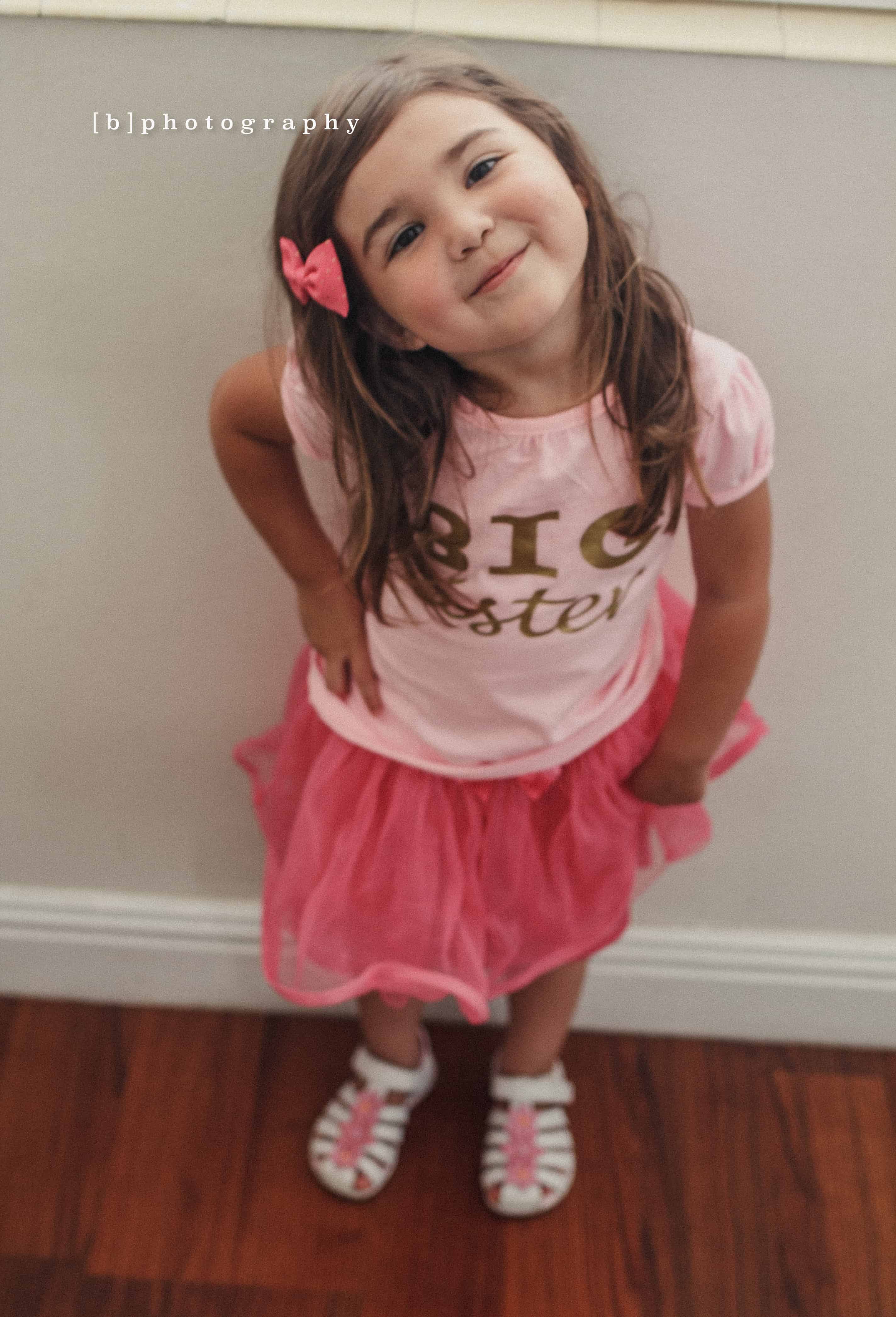 Smiling Girl with a bow in her head wearing all pink with a hand on her hip