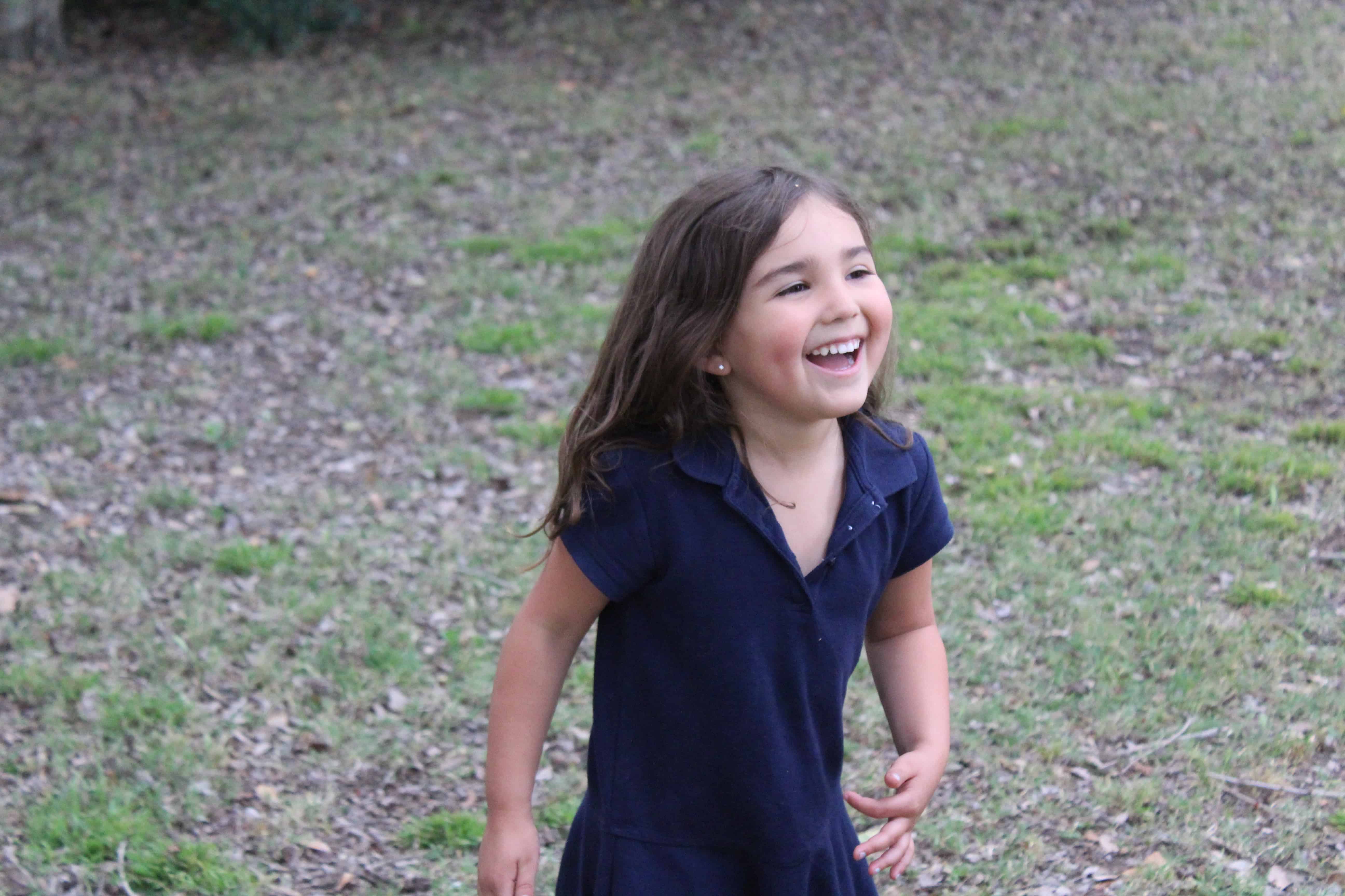 Little girl walking outside a big smile on her face while she plays