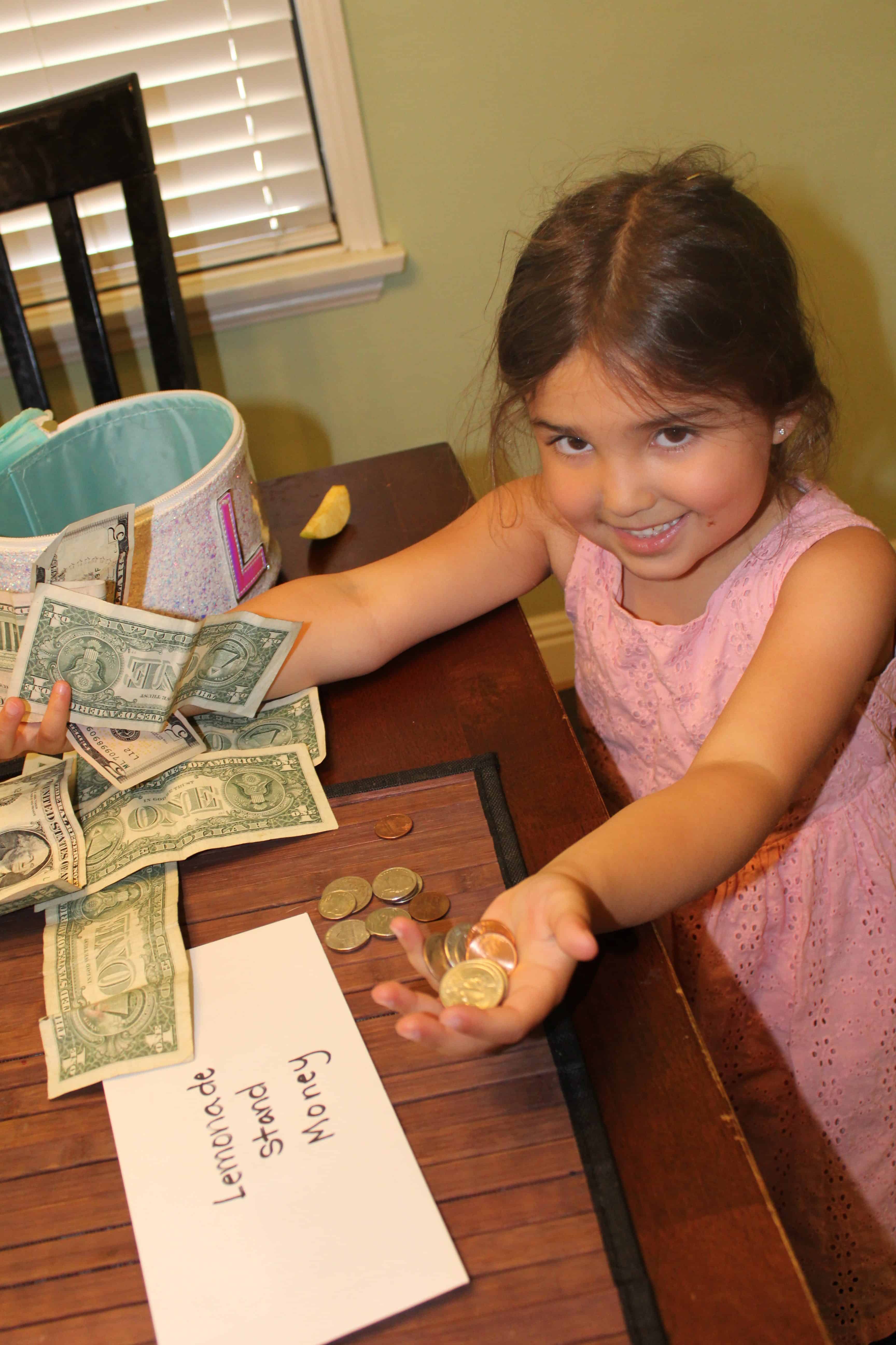 A little girl holding out Quarters and Dimes