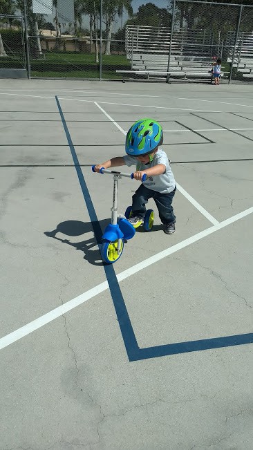 Three year old riding a scooter