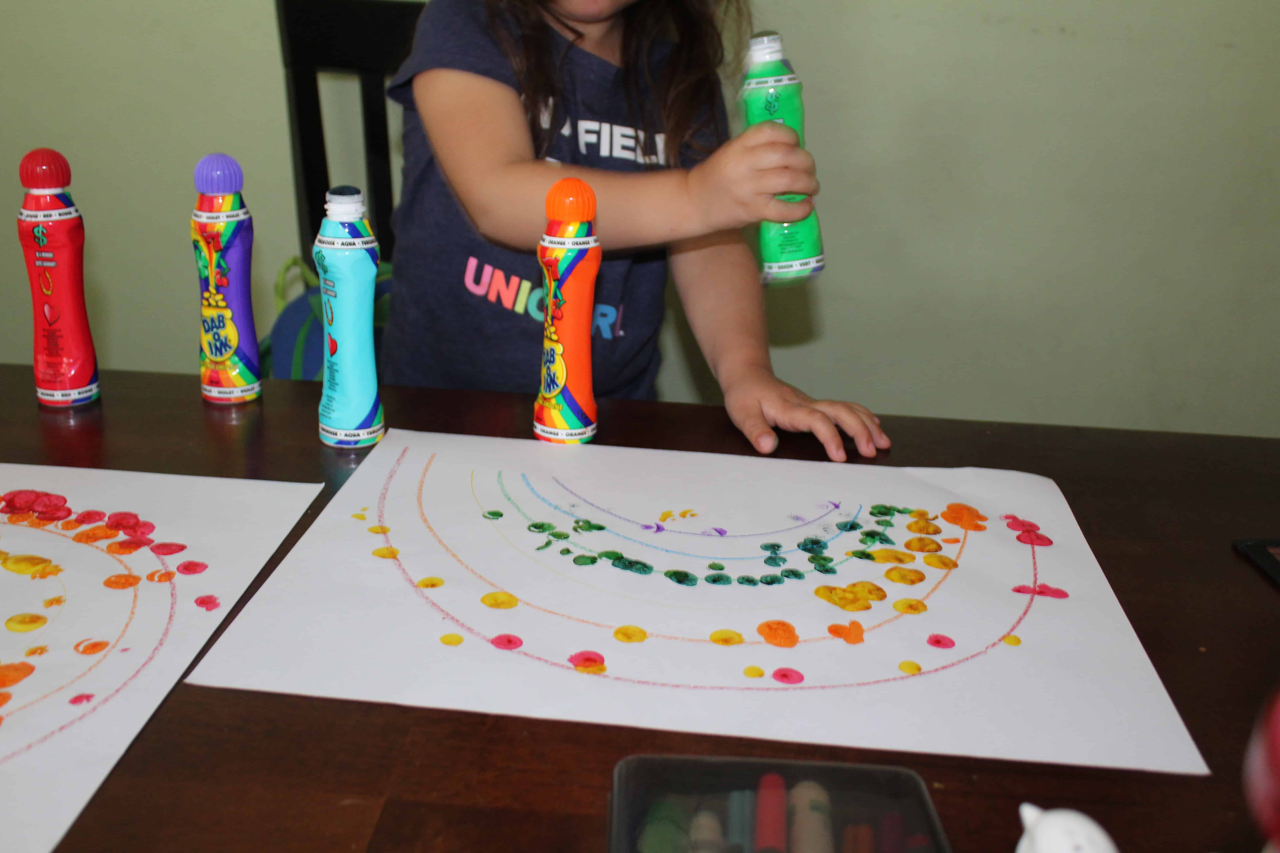 toddler making a rainbow with do a dot markers