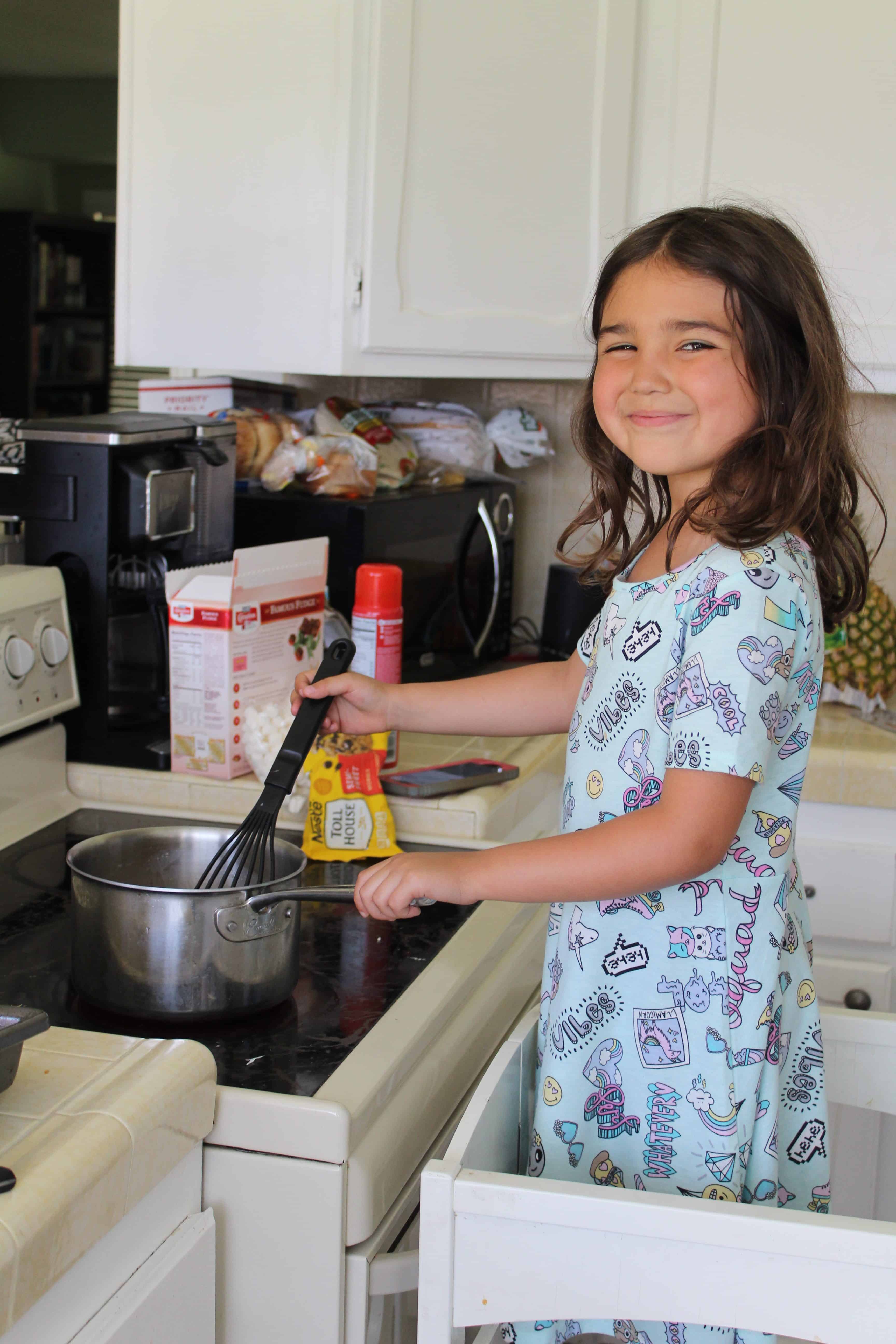 Child helping with the dinner meal mixing on the stove.