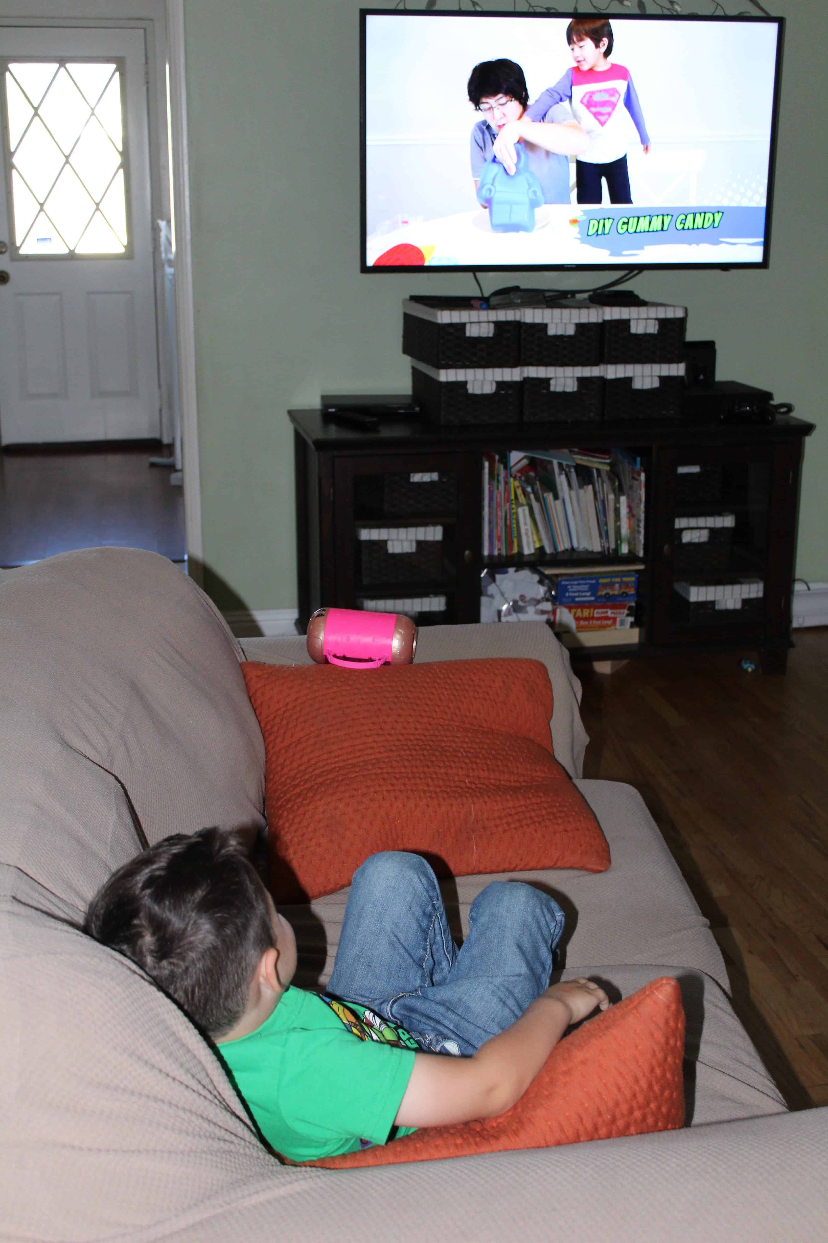 Child sitting on a sofa enjoying screen time on the TV.