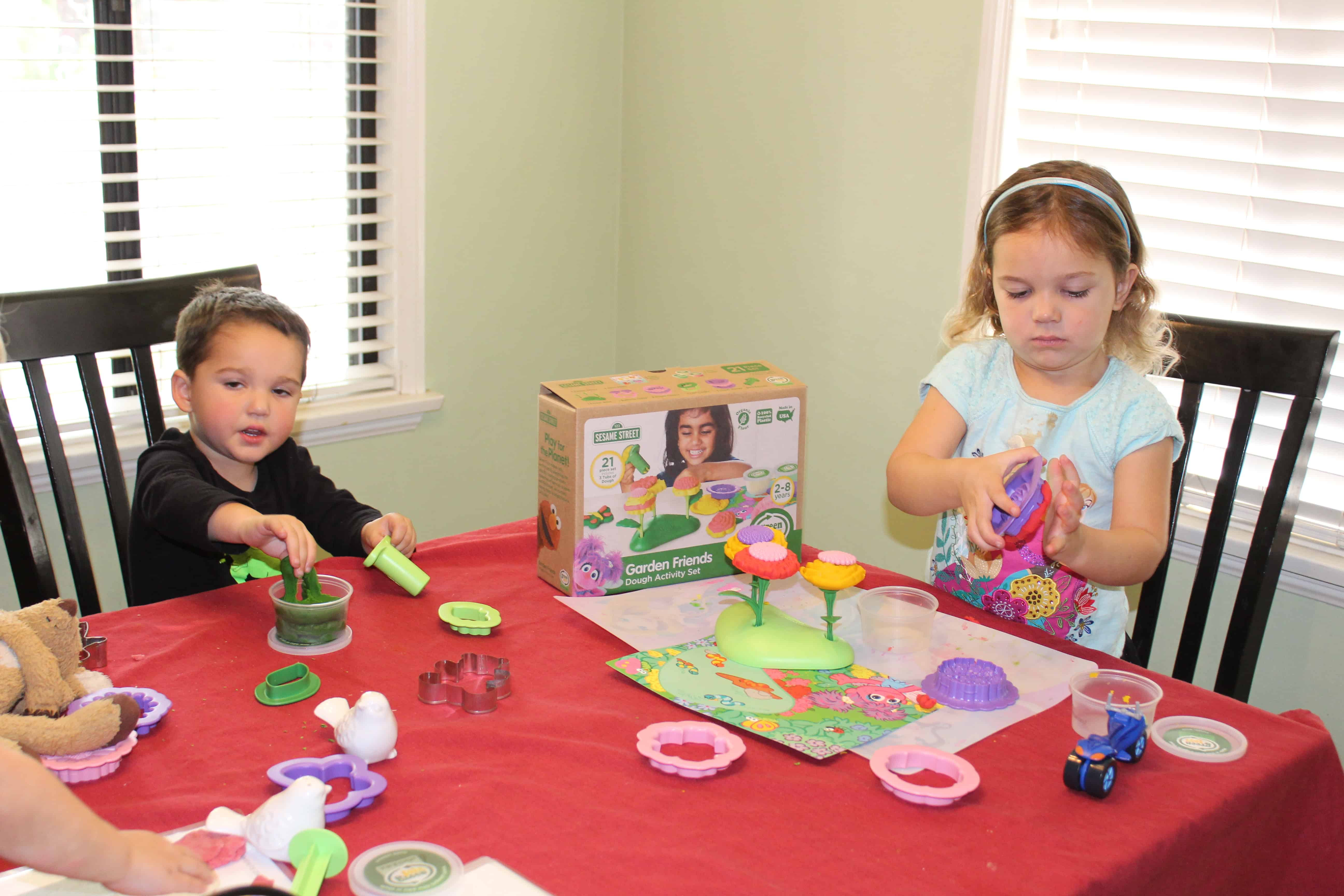 Two toddlers seated at a table playing quietly with play dough