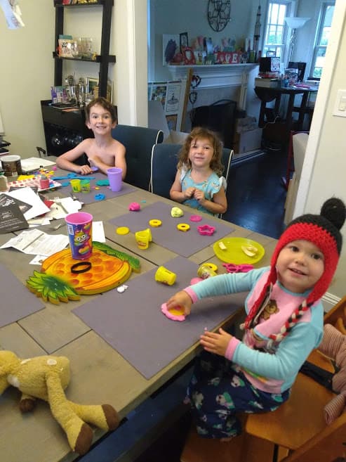 Three children sitting around the table during their breakfast invitations. 