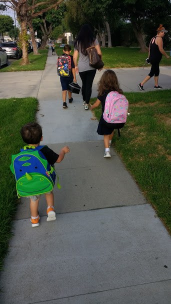 Two children walking to school with backpacks on.