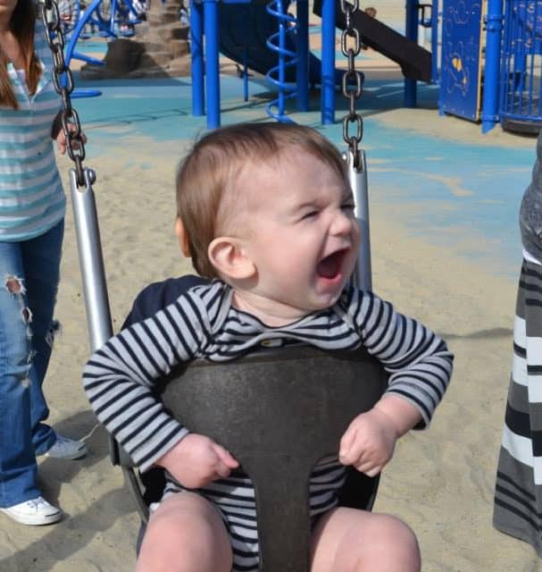 Baby sitting in a swing at a park