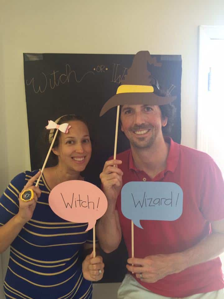 Two adults with "Witch" and "Wizard" pink and blue signs.