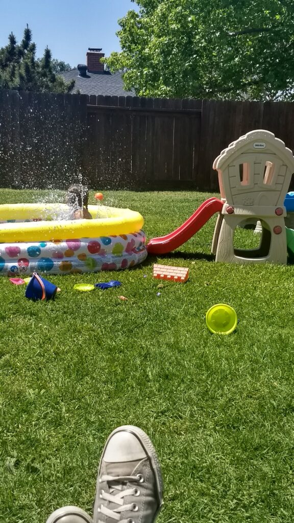 kids playing in backyard, mom with feet up