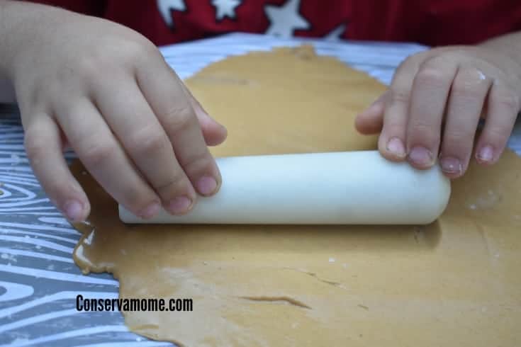 toddler rolling out peanut butter playdough
