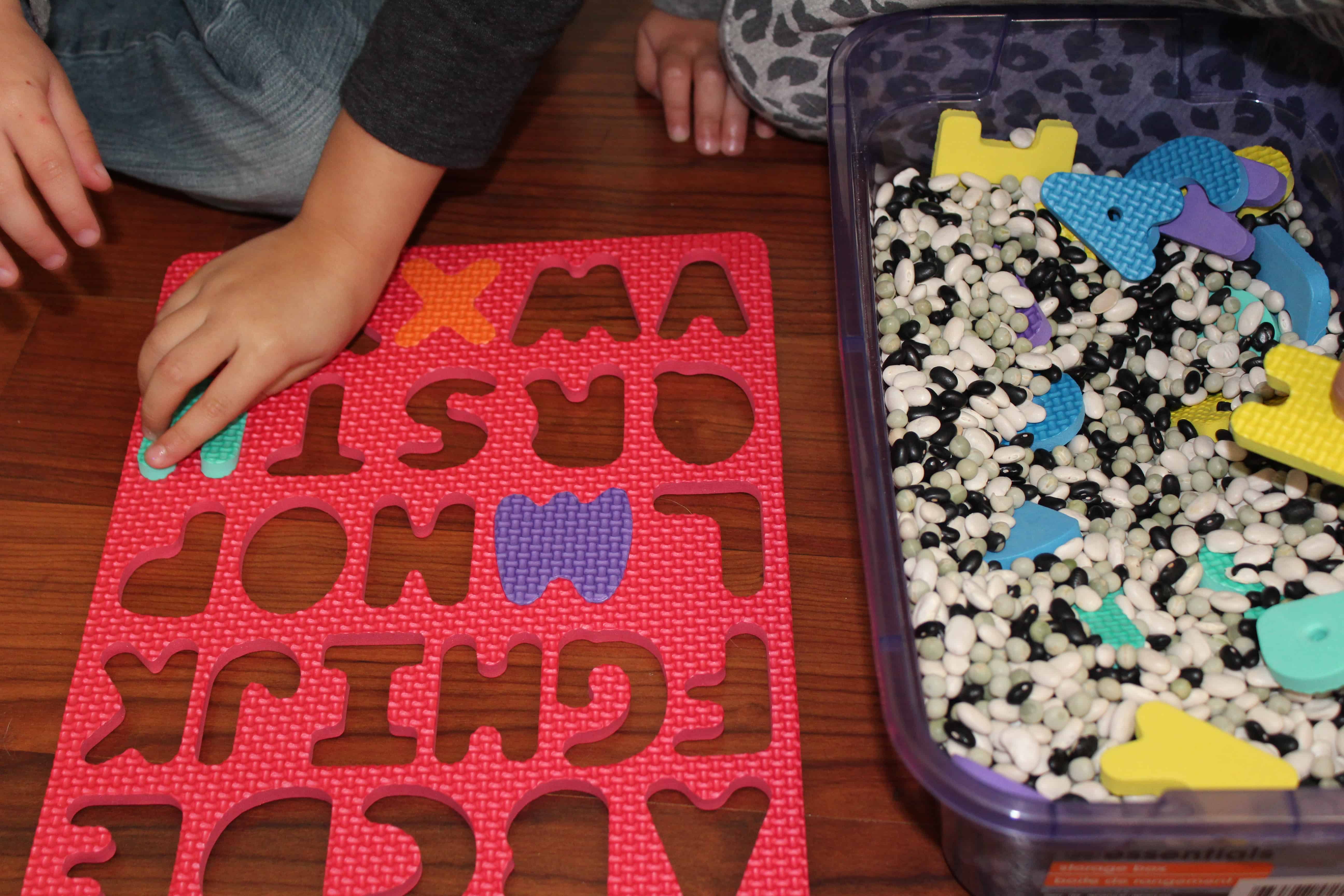 Children playing with a foam letter puzzle and sensory bin