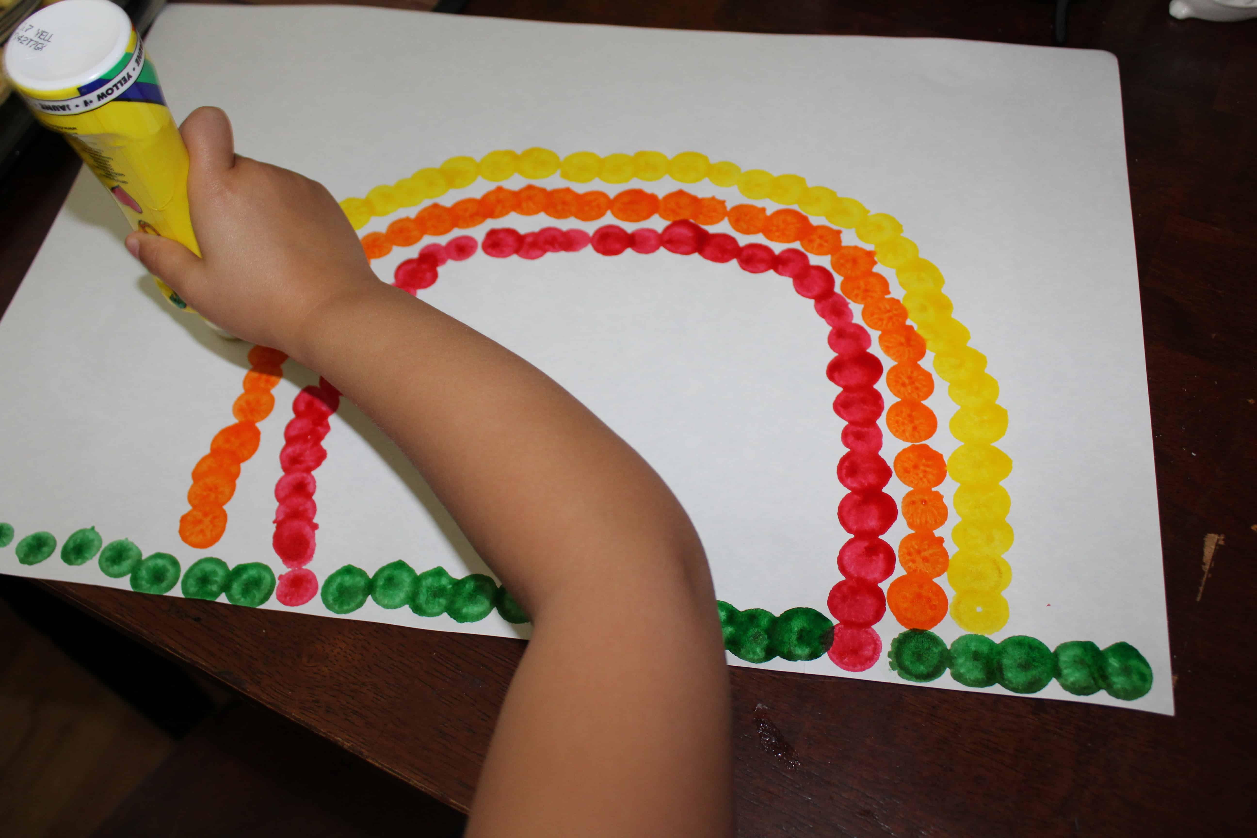 Piece of paper with grass. Also an orange, red, and yellow arch drawn on it. 