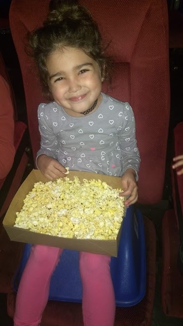 toddler eating popcorn at the movies