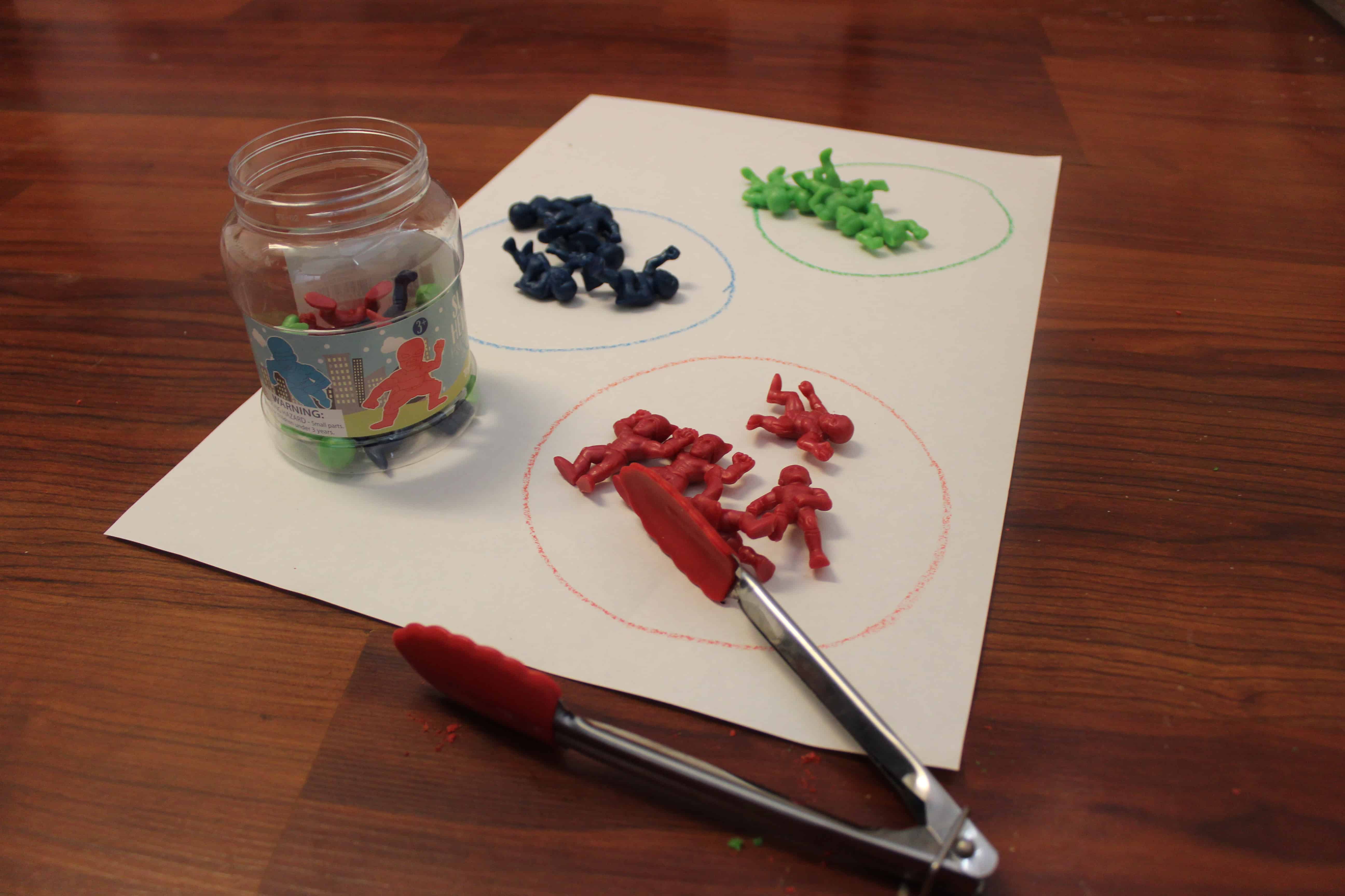 A jar full of plastic Army men and a set of Tongs.