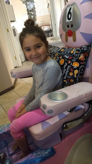 toddler getting a manicure in small massage chair