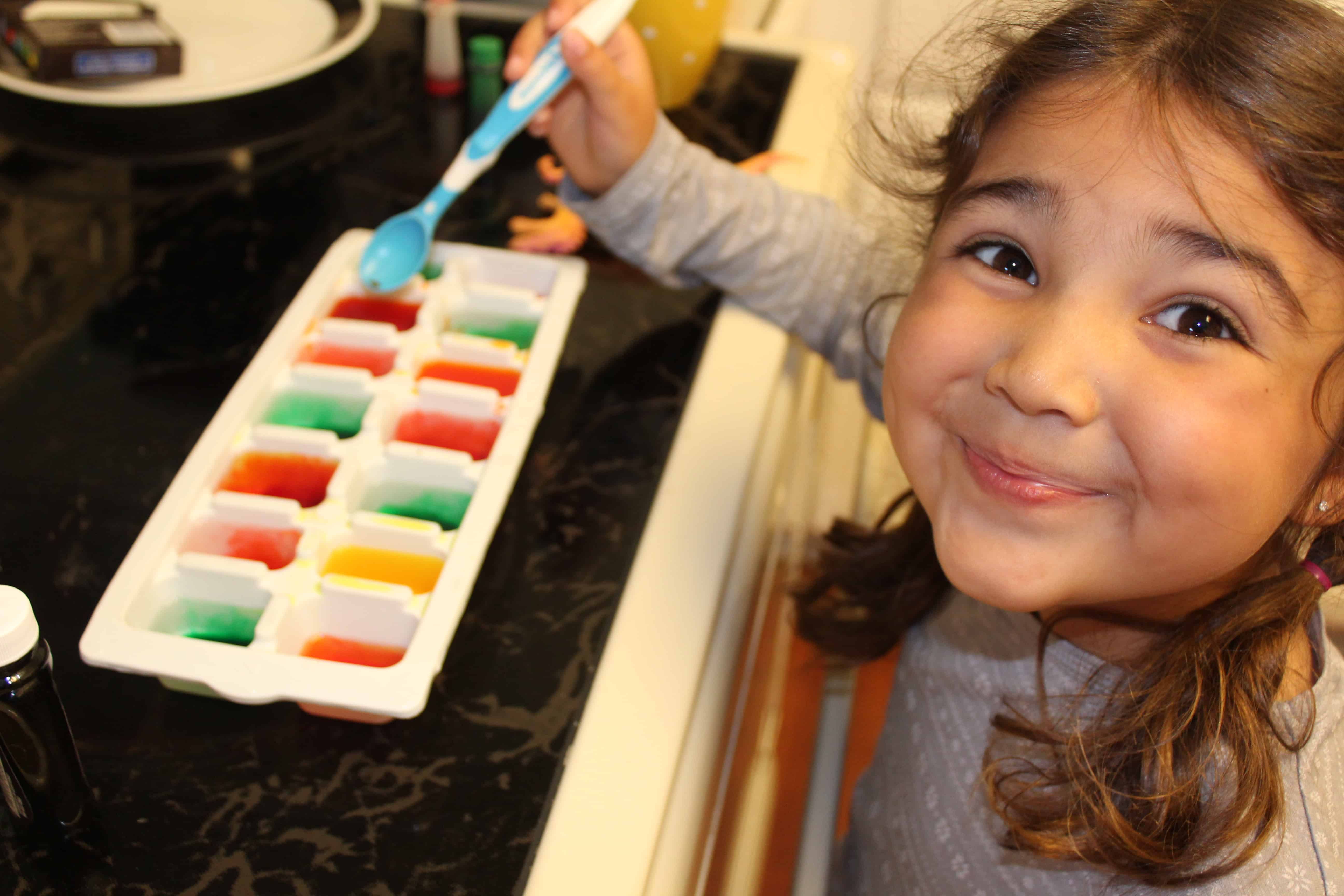 Child smiling with ice tray full of water and food coloring