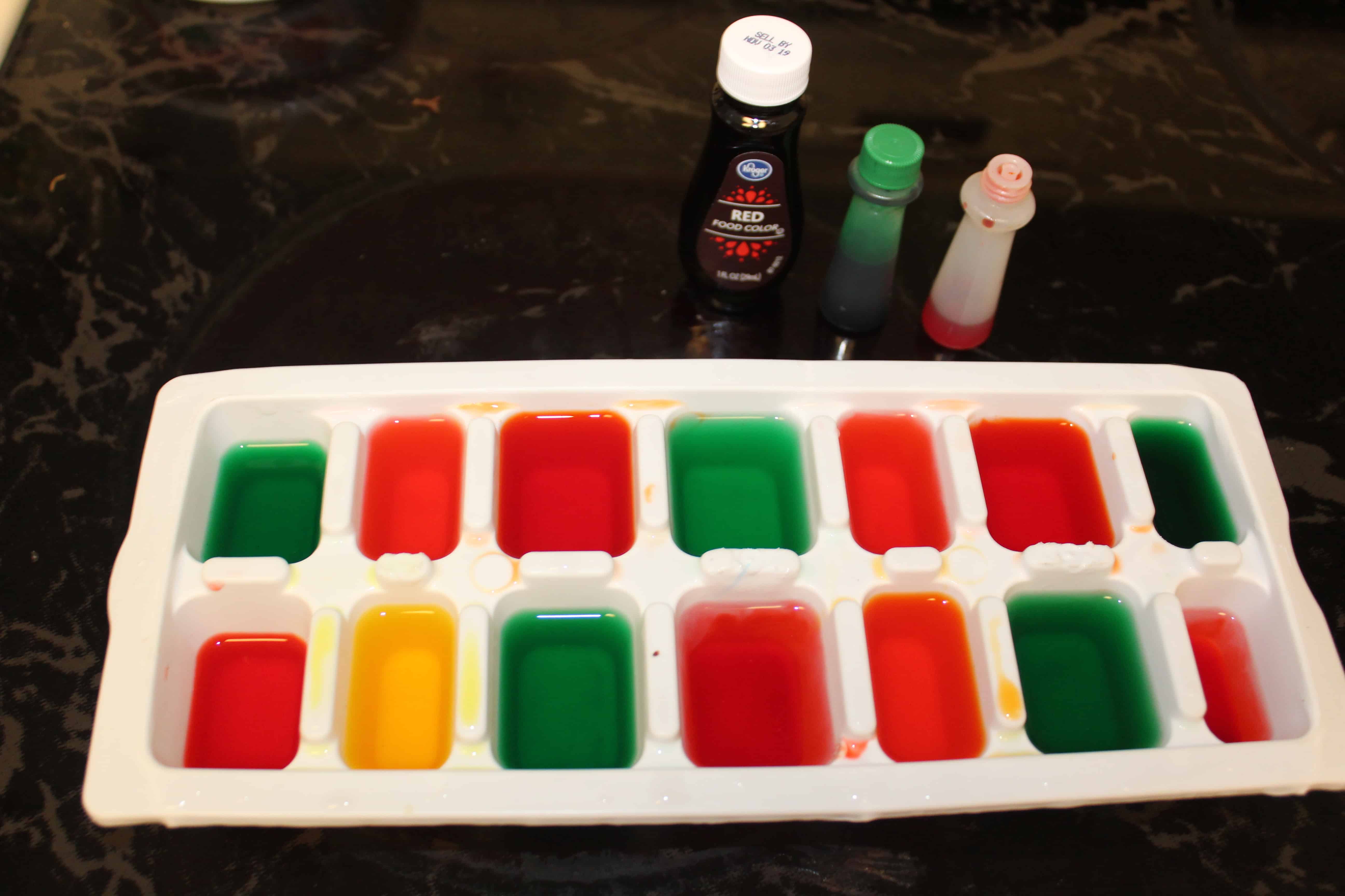 Ice tray full of red, orange, green and yellow food dye paint
