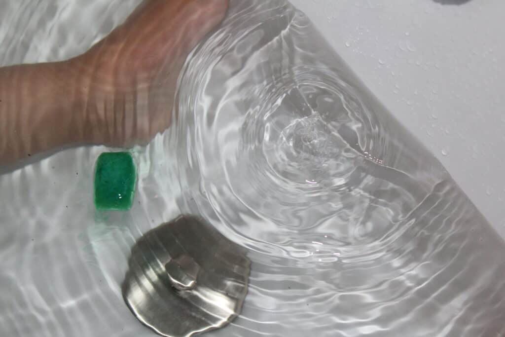 preschooler playing with colored ice cubes in the bath