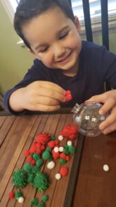 Little boy making diy handmade ornament using pom poms