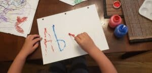 a child tracing their name with a qtip dipped in paint