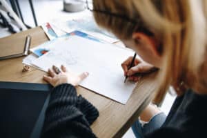 woman sketching on white paper with pencil as a form of art therapy