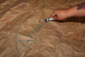 child circling their name, written on a piece of butcher paper